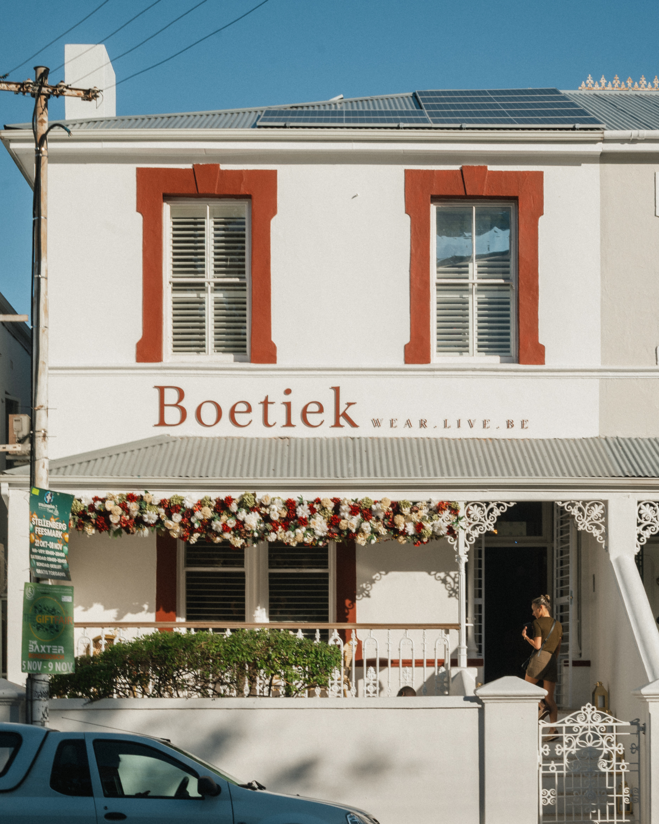 Two-story building with 'Boetiek' and 'Boshoff Brönn Smit' signage on a clear day.
