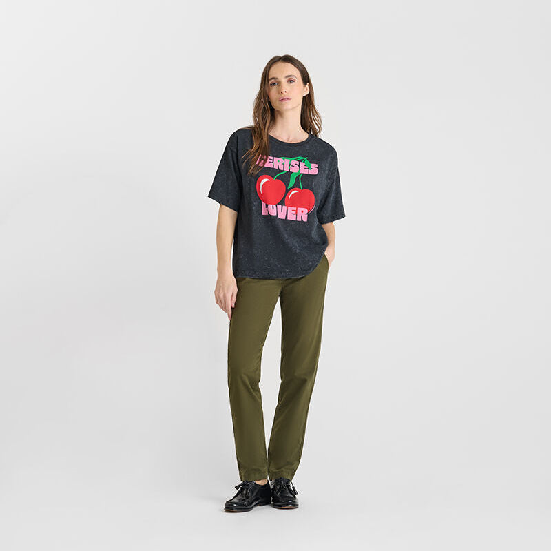 Woman wearing a black t-shirt with red hearts and text, standing against a white background