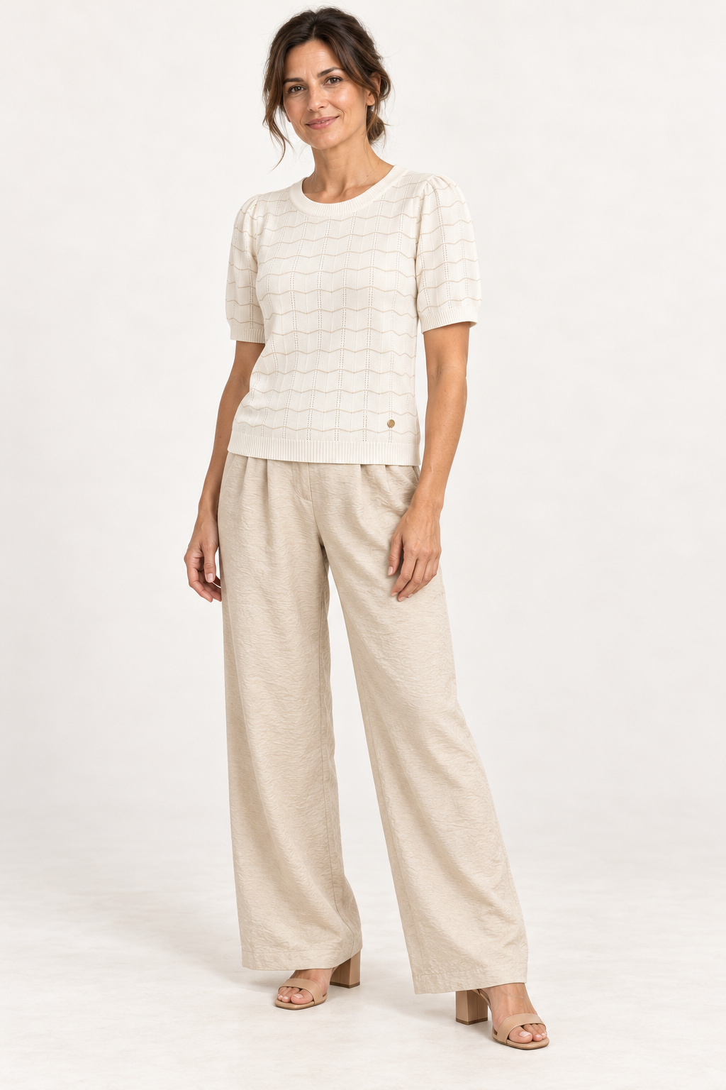Model wearing the Smashed Lemon white and gold pointelle knit top with sand wide-leg trousers
