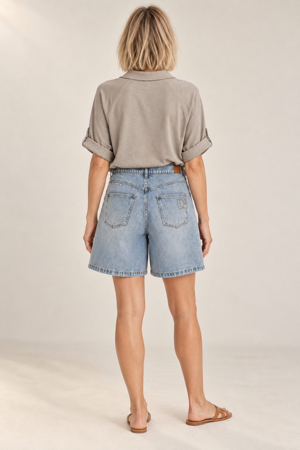Model wearing the Lova Short in Blue from the back, with a grey shirt tucked in