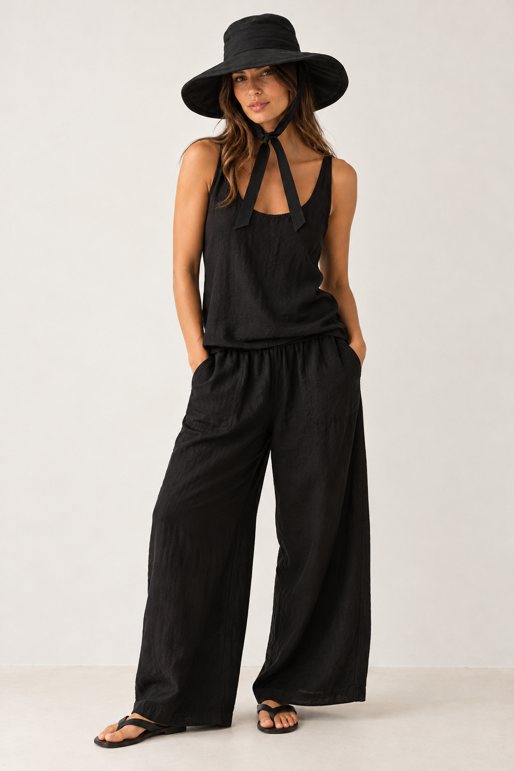 Full-length look with the black Poppy canvas hat, a black linen vest and wide-leg pants