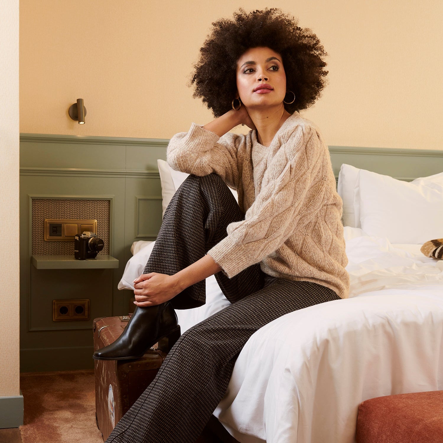 Woman sitting on a bed in a bedroom setting wearing smashed lemon