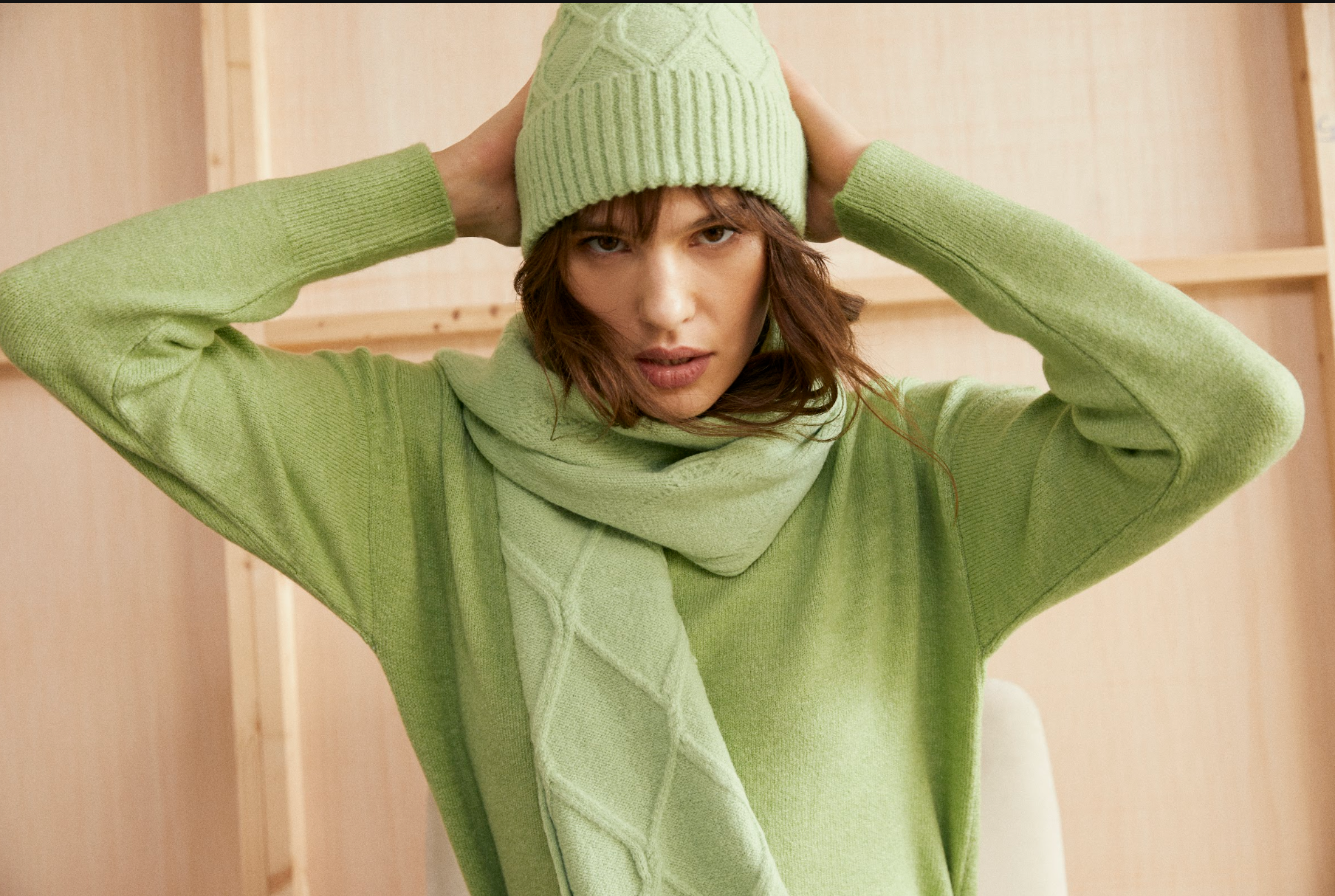 Close-up of the Andam green knit jumper styled with the matching knit beanie and scarf.