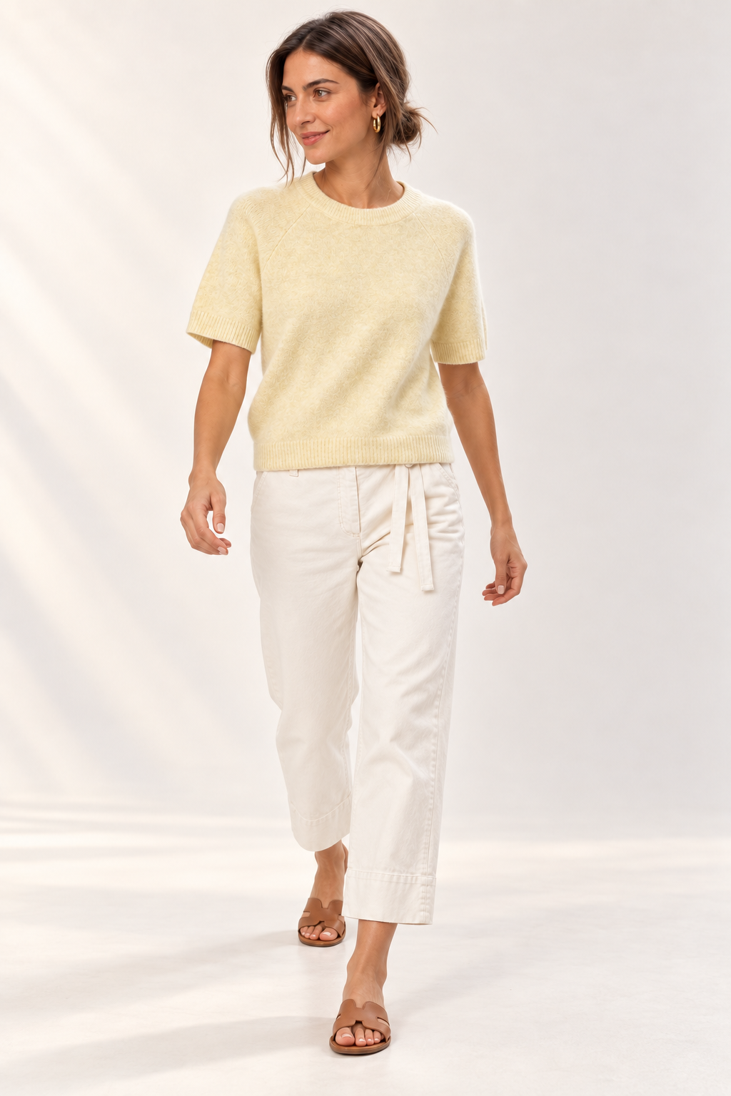 Model walking in the YAYA Raglan Short Sleeve Knit in Reed Yellow Melange and off-white denim