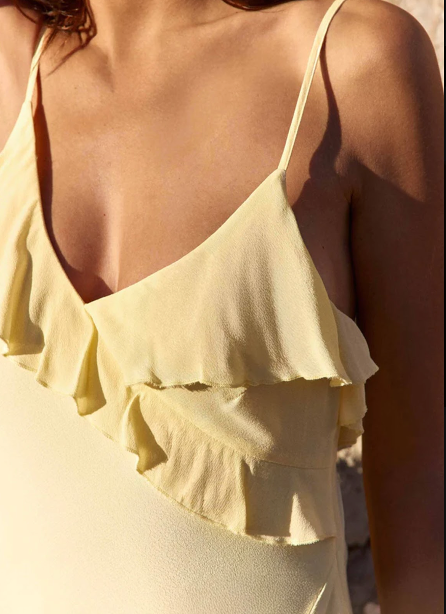 Close-up of the cascading ruffle and V-neckline on the La Petit Étoile Rosilda Dress in pale yellow