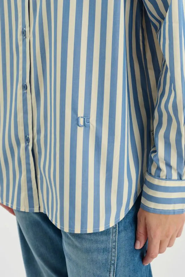Close-up of Le Temps des Cerises striped shirt showing curved hem, button placket and vertical sky blue stripes