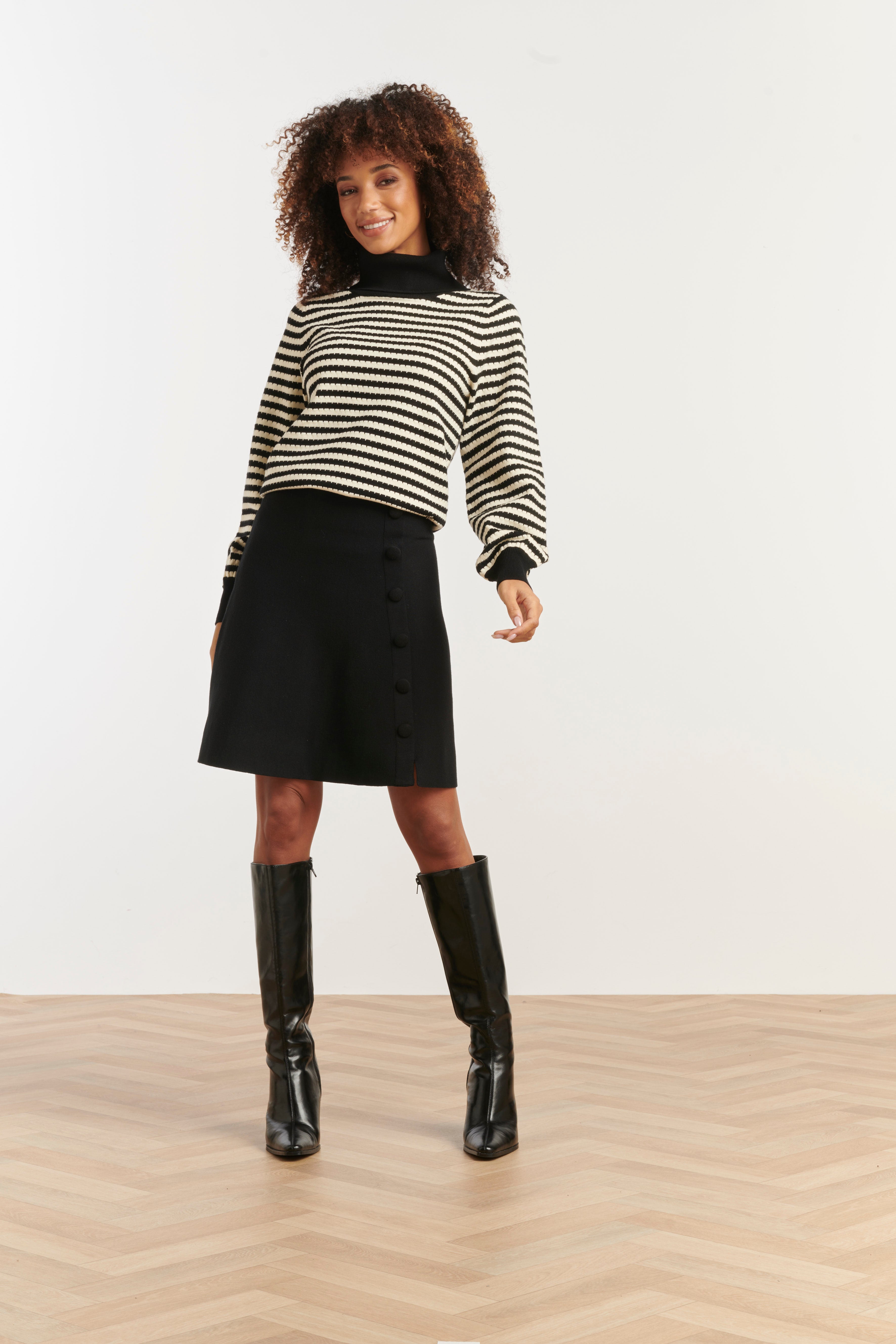 Smashed Lemon turtleneck knit top in black and off-white stripe, cropped fitted silhouette with long sleeves, front angled view with hands by sides
