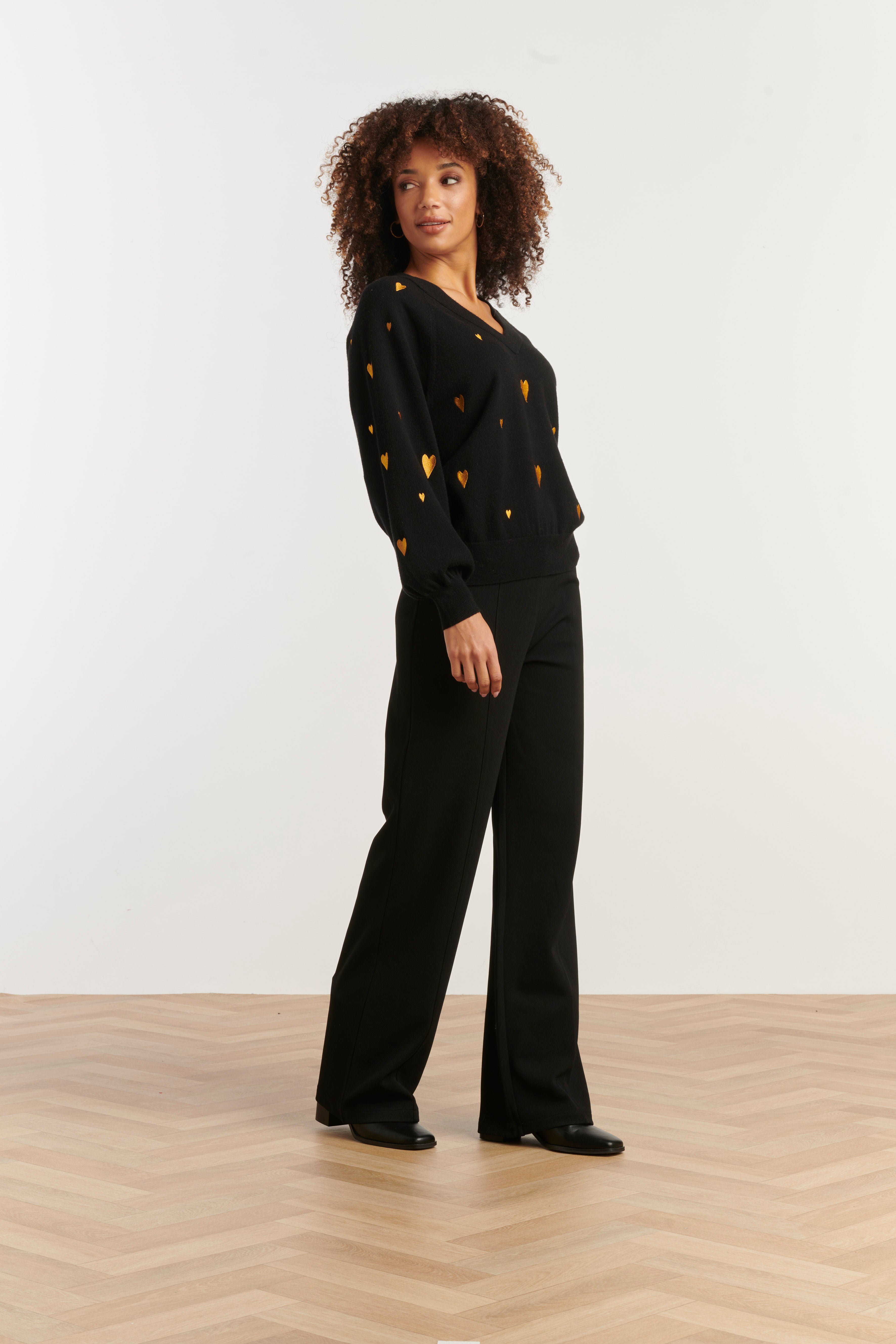 Smashed Lemon V-neck knit top in black with scattered gold heart print, long sleeves, three-quarter angle view