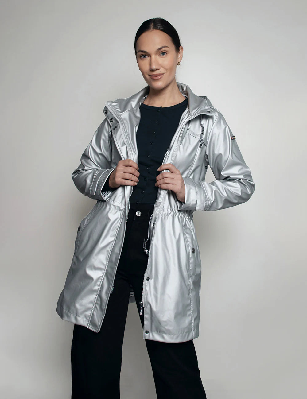 Person wearing a silver raincoat against a plain background Batela Boetiek