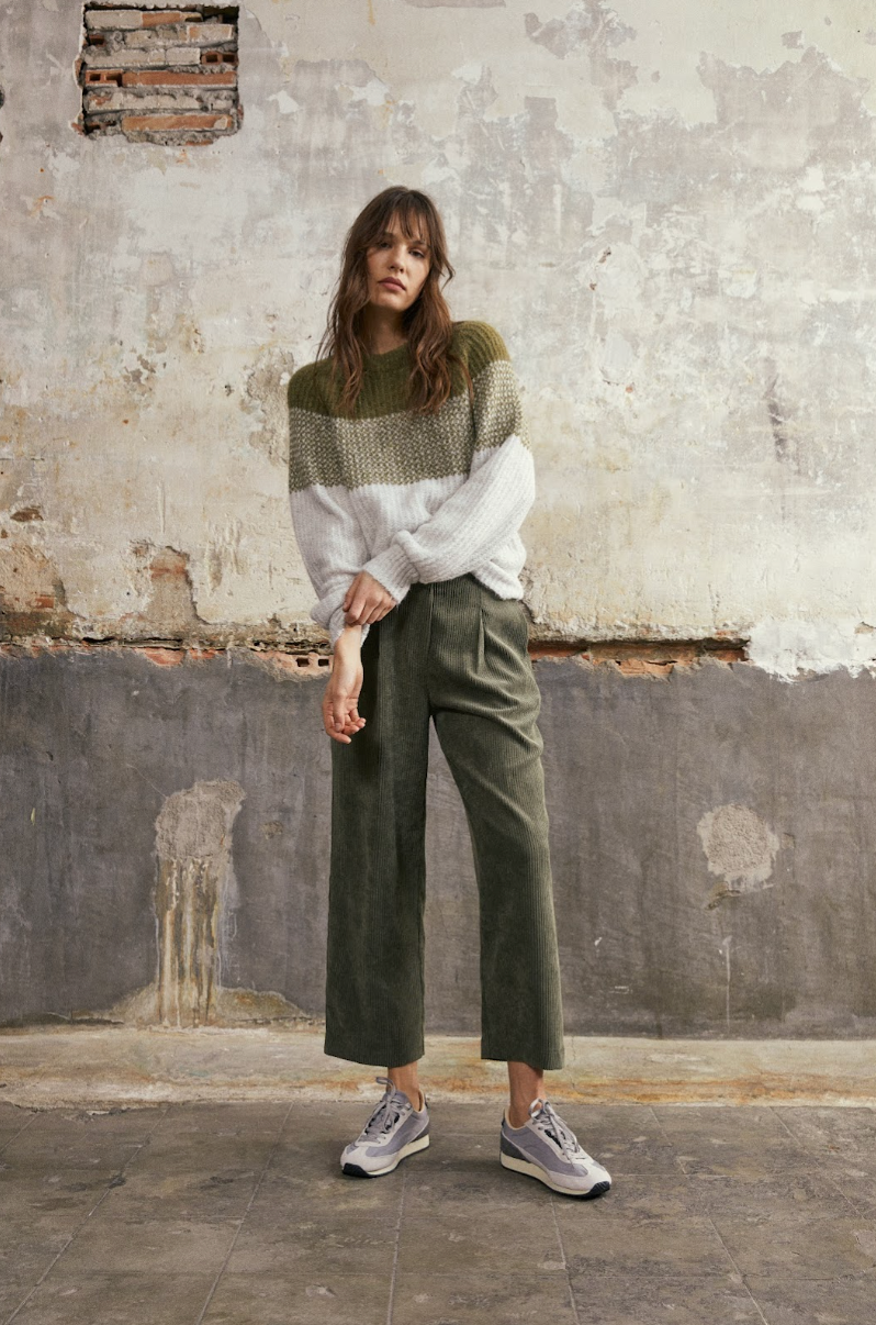 Model wearing the Andam colour block knit jumper in khaki and cream styled with khaki corduroy trousers.