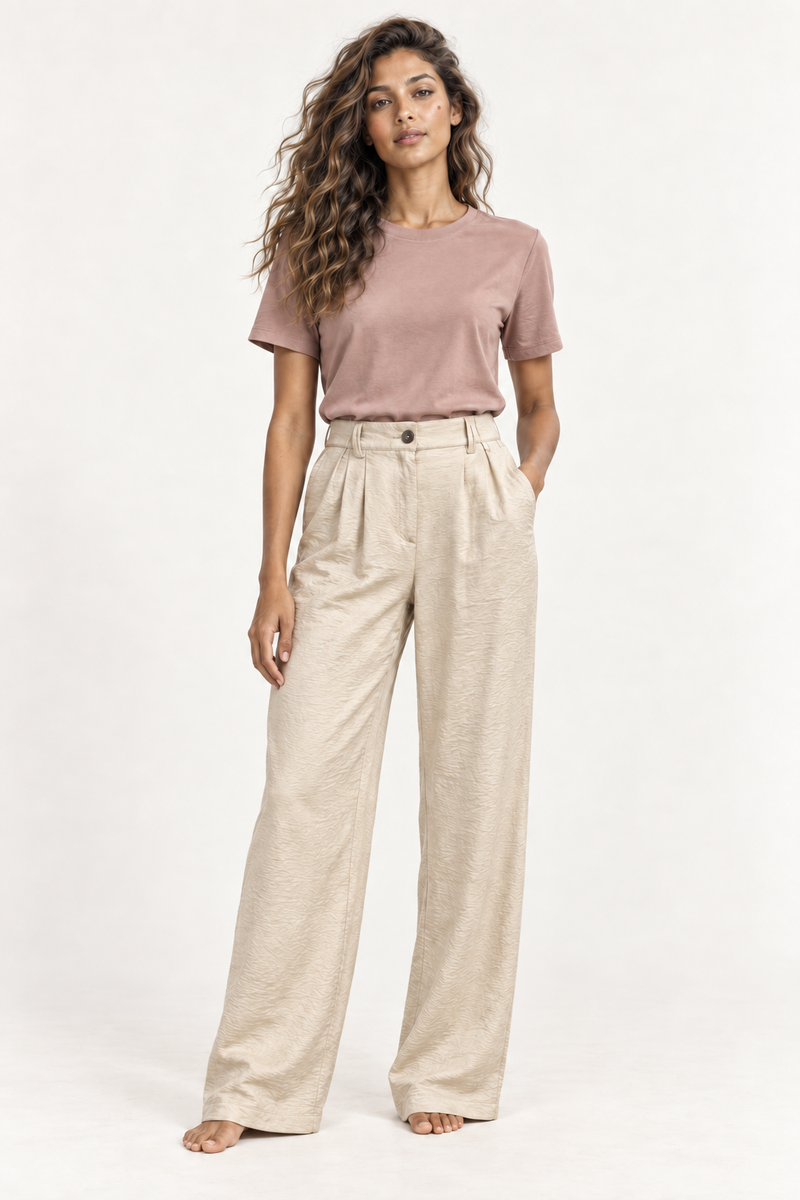 Model wearing the Andam beige pleated wide leg satin pants with a rose tee, front view