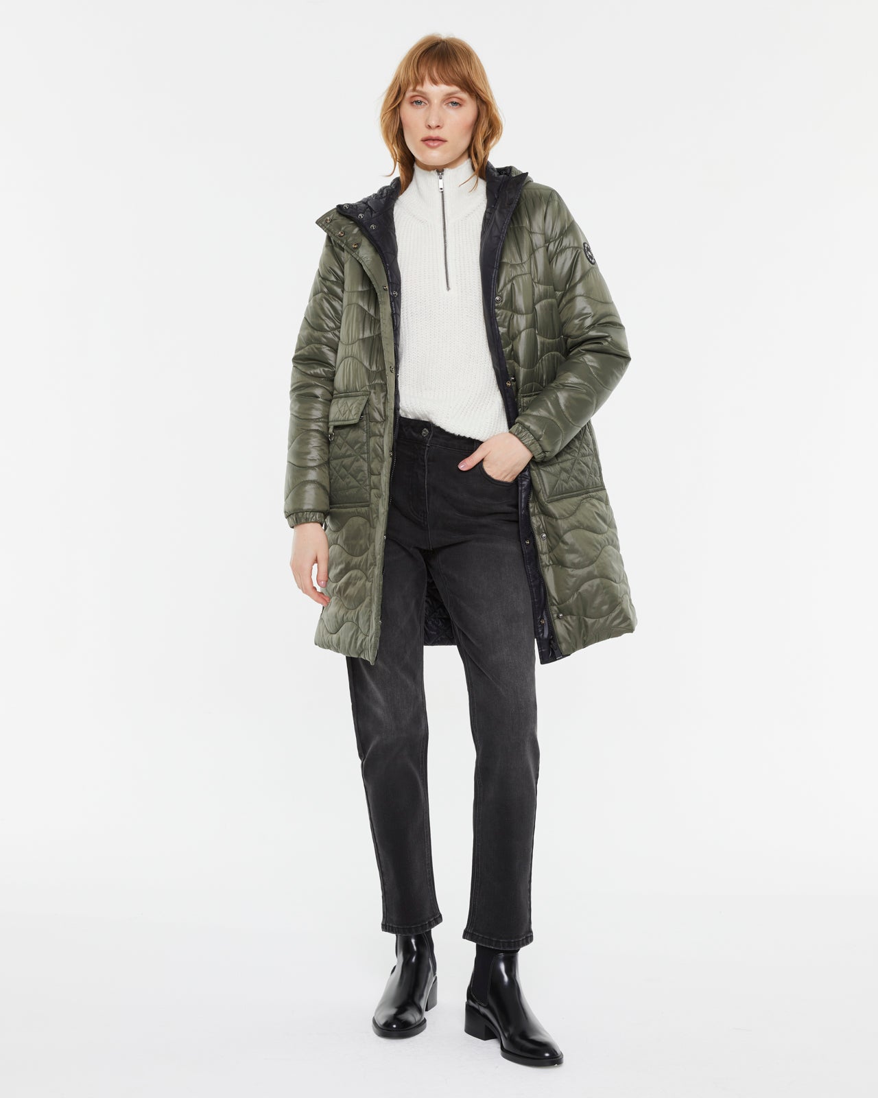 Model wearing Andam quilted parka in khaki with hood, white knit sweater, black jeans and ankle boots