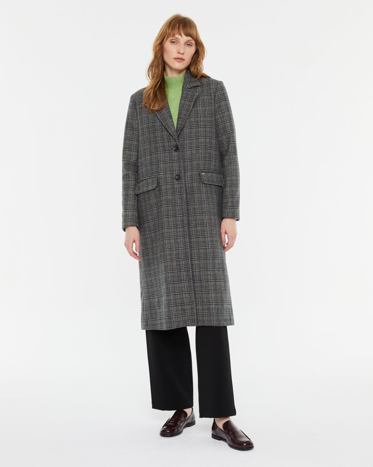 Andam tailored coat in grey check worn with a green knit, black trousers and burgundy loafers
