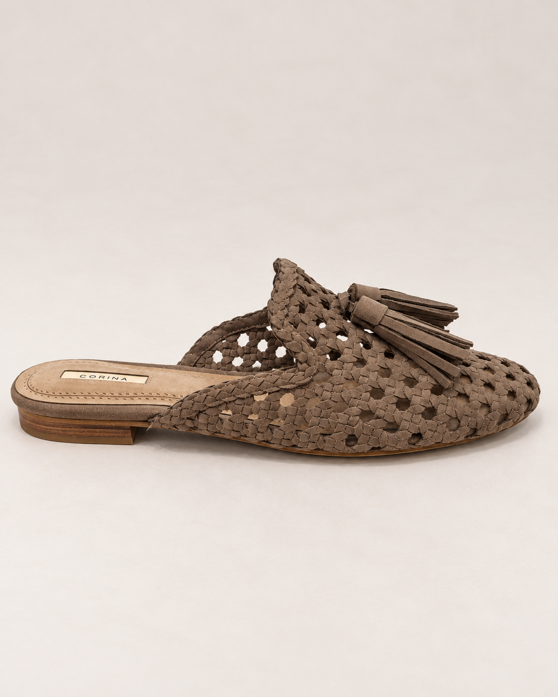 Corina Backless Slipper Shoe in Taupe, side view showing intricate woven upper, pointed toe, tassel detail and low stacked heel