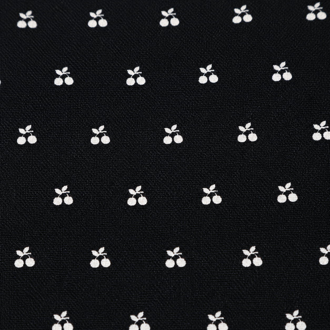 Close-up of Gordon Smith black fabric featuring a delicate white cherry print, highlighting the lightweight textured fabric and playful all-over pattern.