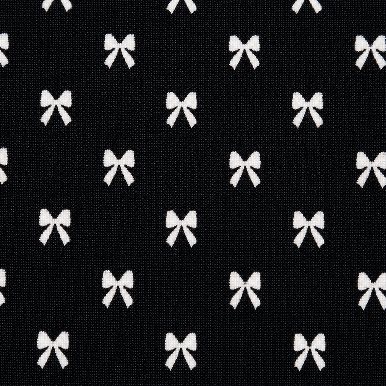 Close-up of the Gordon Smith Bow Tie Print Pant fabric, featuring a black textured base with a delicate white bow print, highlighting the playful all-over pattern and lightweight material.