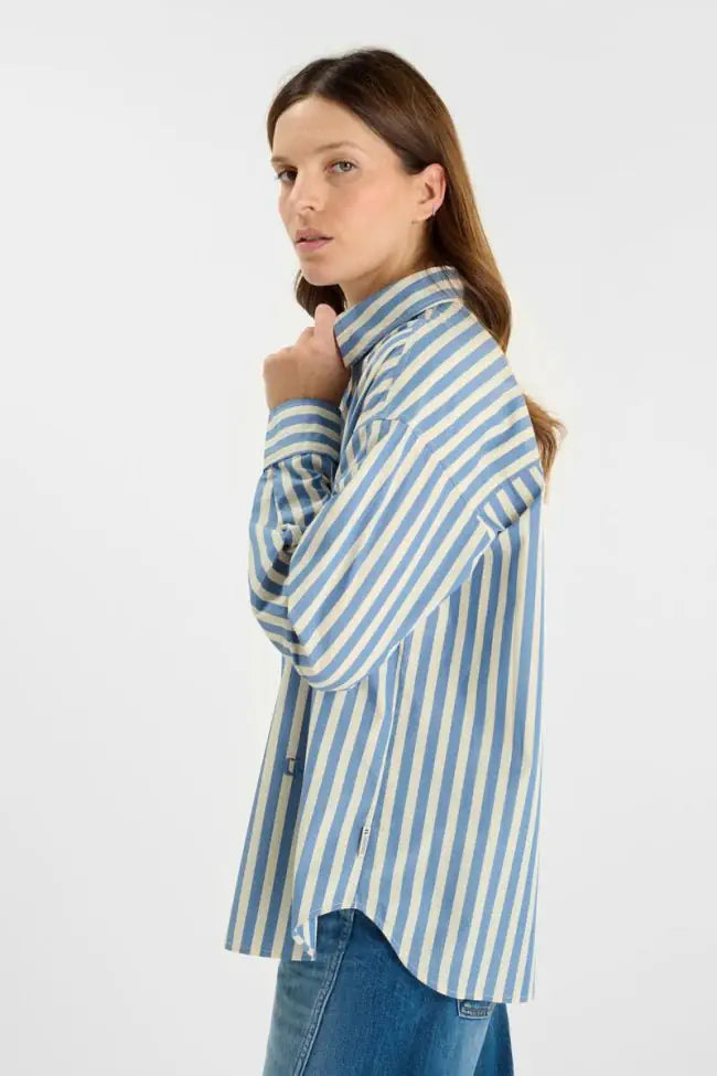 Side profile of Le Temps des Cerises sky blue striped oversized shirt with long sleeves and curved hem