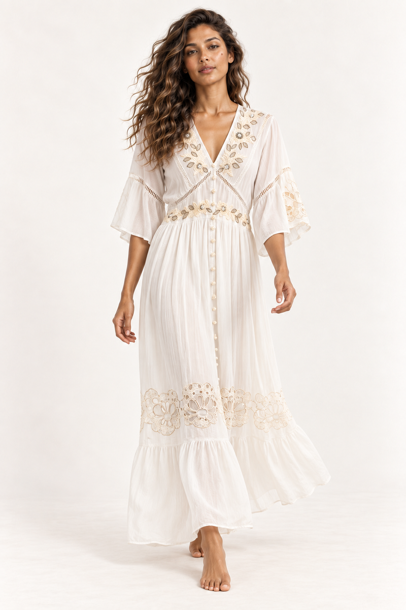 Piti Cuiti gold embroidered button front maxi dress in white shown walking with flowing tiered hem