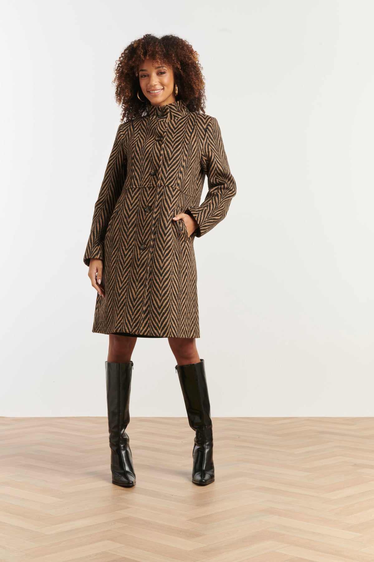 Smashed Lemon printed coat in black and brown, knee-length with high collar, front view with hands by sides