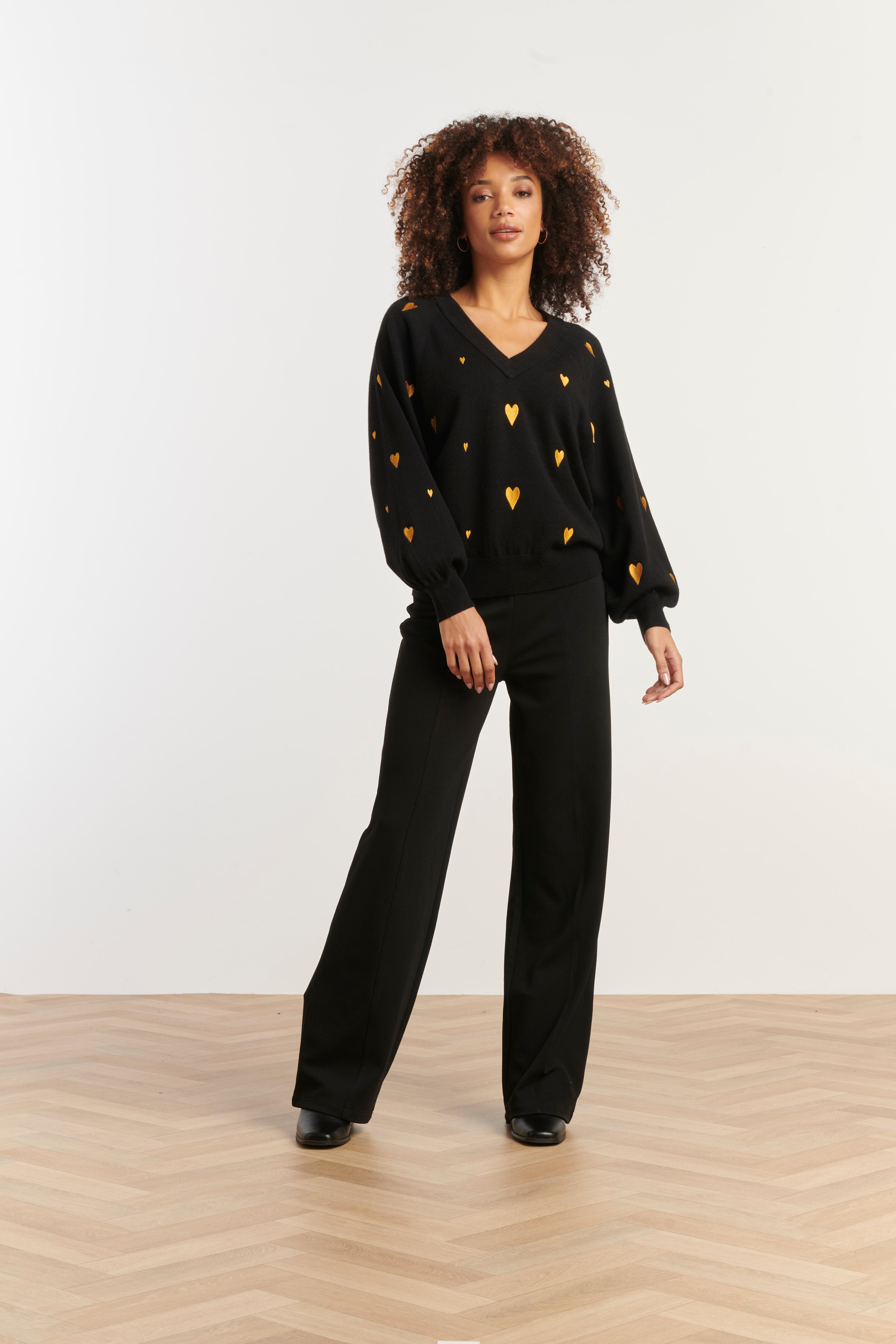 Smashed Lemon V-neck knit top in black with scattered gold heart print, long sleeves, front view
