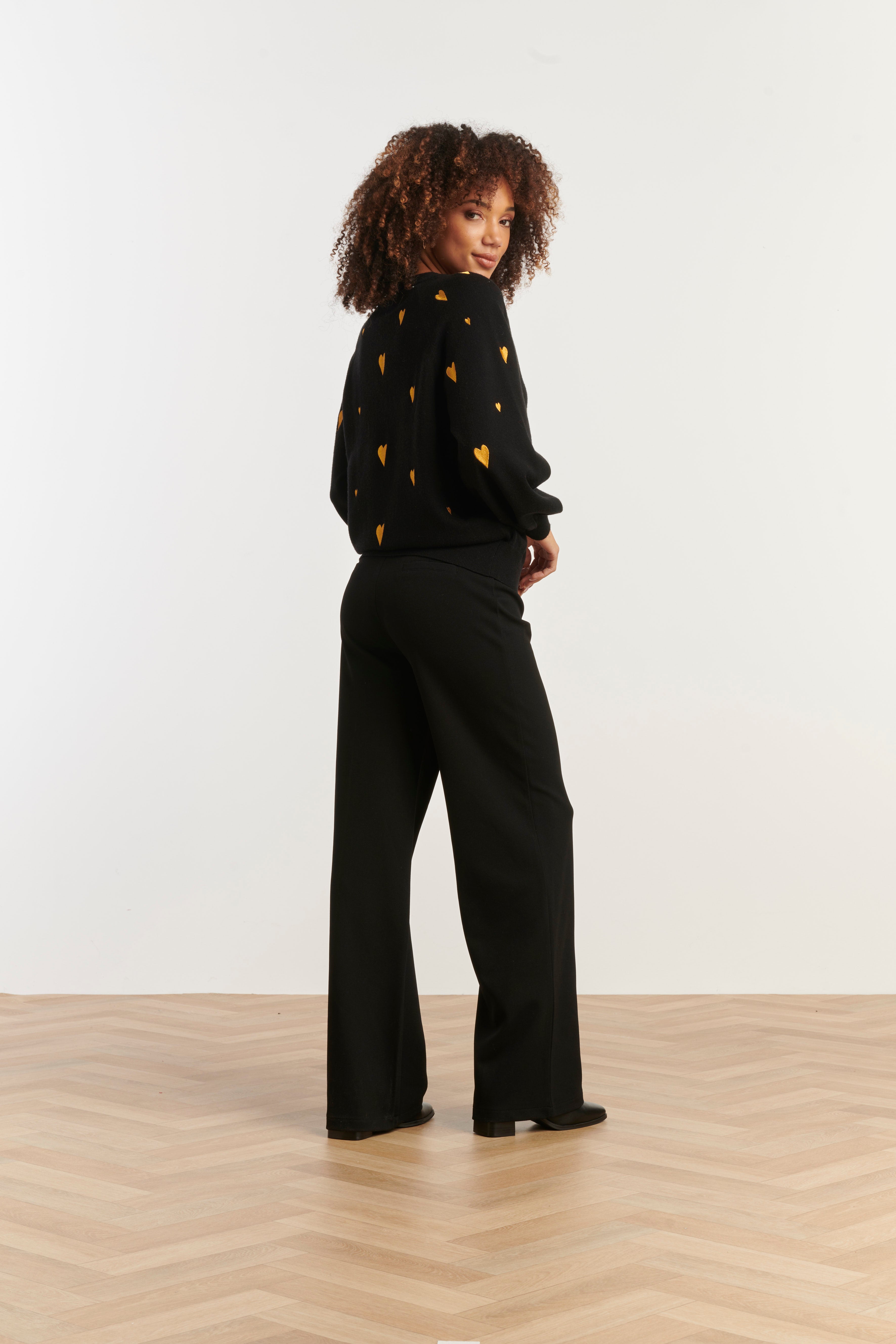 Smashed Lemon V-neck knit top in black with scattered gold heart print, long sleeves, side view