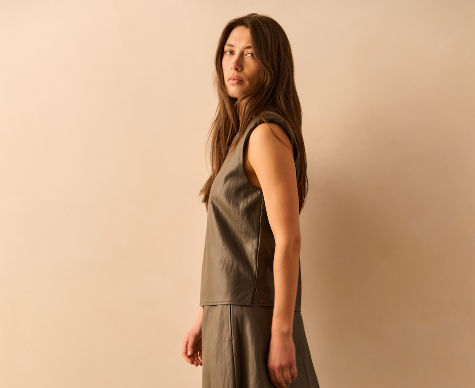 Side view of the YAYA Faux Leather Spencer Top with Shoulder Pads in Dark Taupe Grey featuring a sleeveless design, V-neckline and relaxed contemporary silhouette.